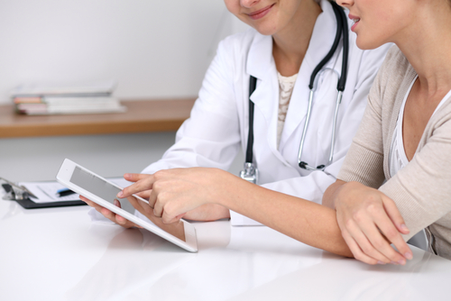 A doctor and a patient are looking at a tablet.