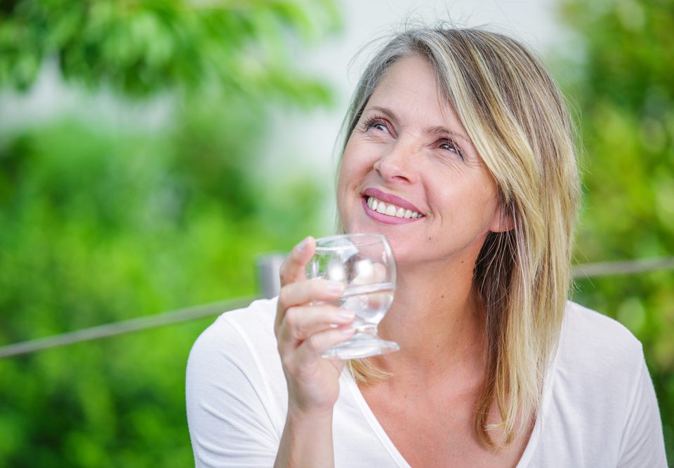 Woman drinks a glass of water outside