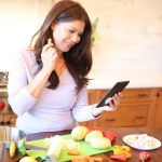 Woman using tablet while preparing food